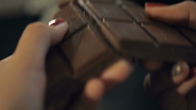 女人打破了巧克力棒。慢动作