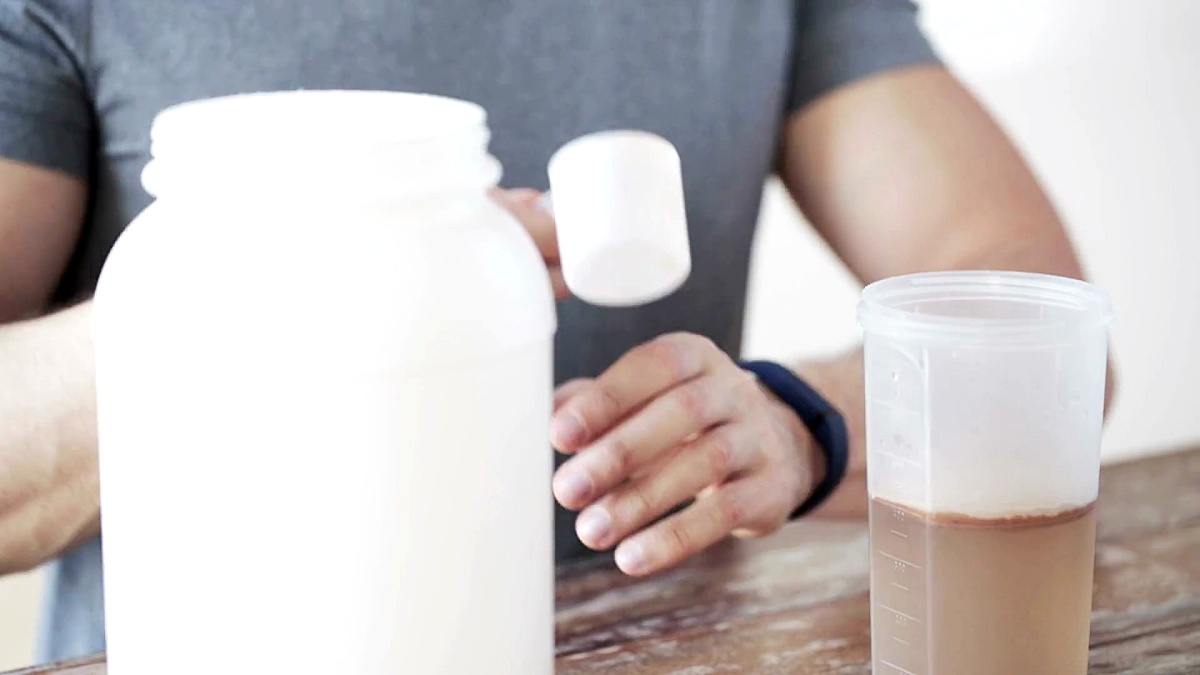 带罐子和瓶子准备蛋白质奶昔的健身跟踪器