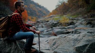 人类探索荒野地区。坐在岩石岸边