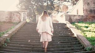 年轻时尚的女人走在城市的老街上，爬上楼梯。女孩在欧洲度假