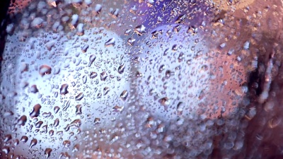 雨点落在车窗上，背景上的交通灯变得模糊
