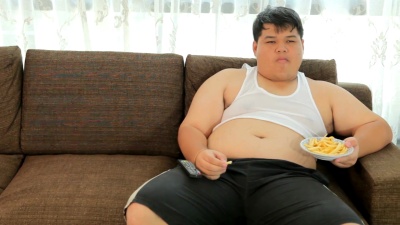 懒惰超重的男性坐着吃快餐