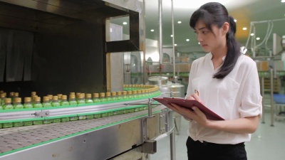 草药保健饮料制造行业的年轻女工正在检查产品的质量。饮用水和饮料的生产