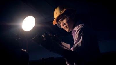 年轻的工厂工程师在工厂工业机器后面操作检查质量