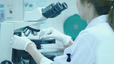 在医院实验室里摆弄显微镜的女科学家技术员