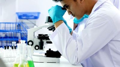 男性研究科学家在研究实验室分析显微镜幻灯片。 分辨率。