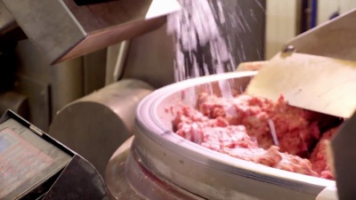 在肉类工厂的特写镜头中，在巨大的肉磨机上加工碎肉中的猪油或肉。