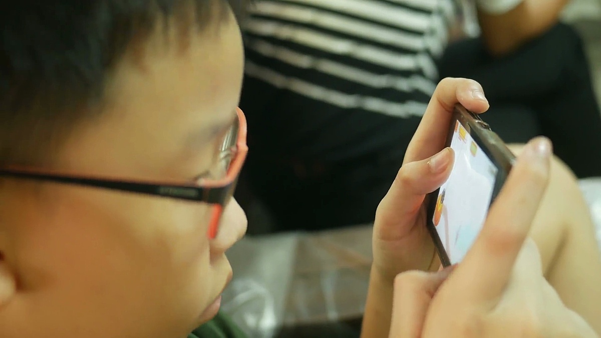 用智能手机玩数码游戏的亚洲男孩