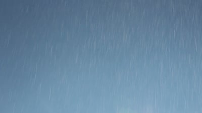 蓝天背景上的水滴。喷雾雨。雨滴使镜头闪光。
