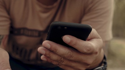潮人坐在长凳上用信用卡打电话。