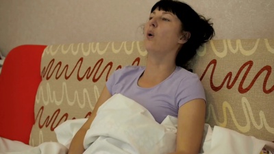 年轻的生病的女人在家里的沙发上咳嗽。这个女孩患有咳嗽和持有组织，流感症状。医疗保健和医学概念。感冒是流感感染。哮喘发作。