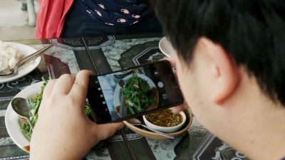 一名泰国男子在午餐前用智能手机在餐厅拍摄食物照片