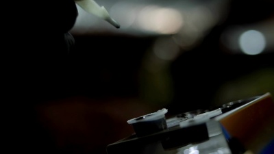 纹身艺术家将机器针浸在一次性墨水杯中。纹身沙龙的黑手套工人。慢动作