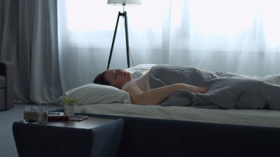 疲倦的女人睡觉时用枕头盖住头和耳朵