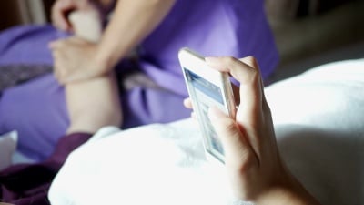 年轻女子用泰式按摩放松并使用电话
