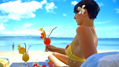 女士在海滩上喝鸡尾酒