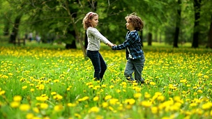 恋爱中的孩子9-10岁，卷发在公园蒲公英空地上纺纱