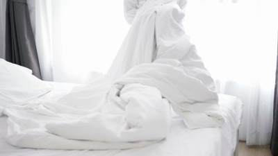 亚洲女子向床上扔白色毯子的特写镜头-库存视频