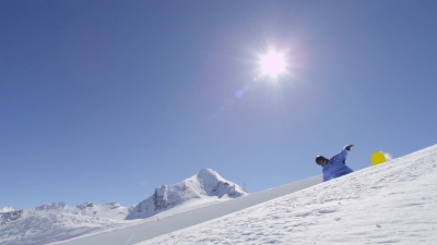 慢动作 年轻的职业滑雪板运动员在半管雪地公园跳过太阳