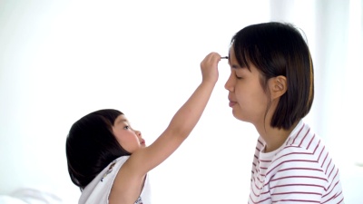 年轻的母亲给小女孩化妆