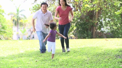 父母和女儿在公园里跑步的慢动作序列