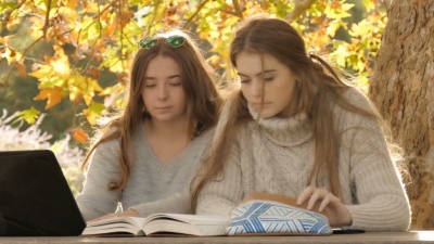 有魅力的女大学女生用笔记本电脑秋季工作学习