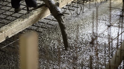 近距离拍摄橡胶软管，水泥通过橡胶软管进入工业现场填充地板，旁边有一个工头