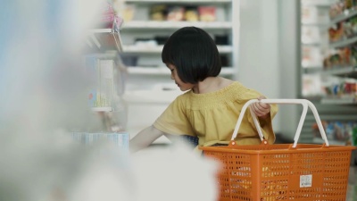 泰国小女孩的注意力集中在超市里挑选和购买一些食物