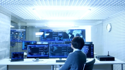在系统控制监控室中，操作员与显示图形、物流、神经网络的多个显示器一起工作。数据中心轻盈，充满了先进的技术。