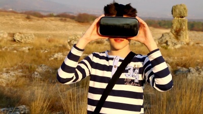 一个小男孩在自然界外面使用虚拟现实眼镜