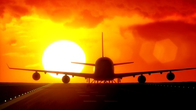 Jet plane departs from airport runway with big sun