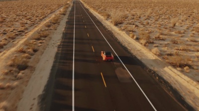 鸟瞰红色经典车在落日荒凉的沙漠公路上行驶