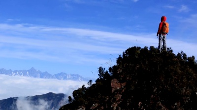 欢呼的女徒步旅行者张开双臂登上山顶