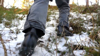 冬日的雪山森林里行走着一双无法辨认的人的双脚。年轻的徒步旅行者爬上雪坡。健康积极的生活方式。旅行的概念。后背视图特写慢动作