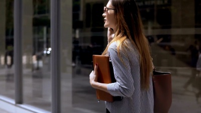 年轻漂亮的女商人戴着墨镜拿着文件在手机上聊天。慢动作