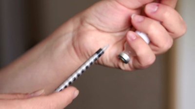女孩在注射胰岛素的注射器里填满。 