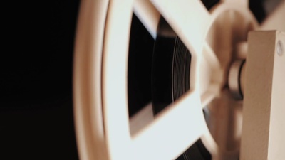 旧的8毫米电影放映机在夜间播放。带电影的卷轴的特写镜头。视频、音频录音机或播放机上带磁带的旋转卷轴