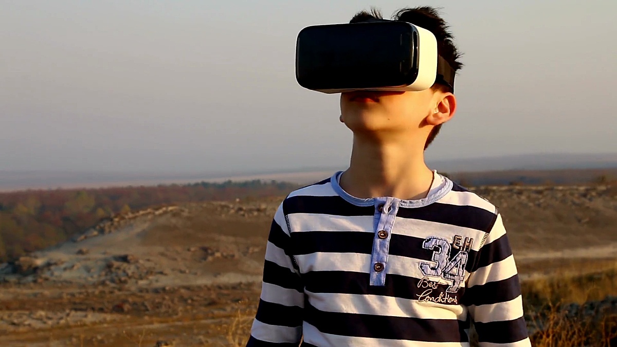 一个小男孩在自然界外面使用虚拟现实眼镜