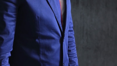 蓝色男士豪华晚礼服，校正袖口，金戒指，怀抱灰色墙壁