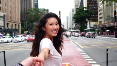年轻的亚洲女孩牵着她男朋友的手-跟我来