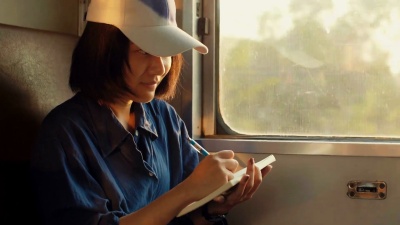 一名亚洲妇女在乘火车旅行时正在写日记。