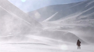 一个孤独的旅行者在雪山的背景下穿过暴风雪。