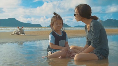 亚洲年轻的母亲和她的女儿和一只狗在海滩上玩耍
