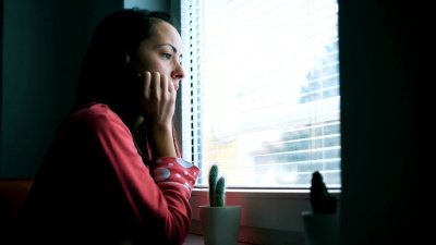 悲伤的女人透过窗户看