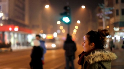 后视图。那个忧伤的深色头发的年轻女孩正在等待绿灯过马路