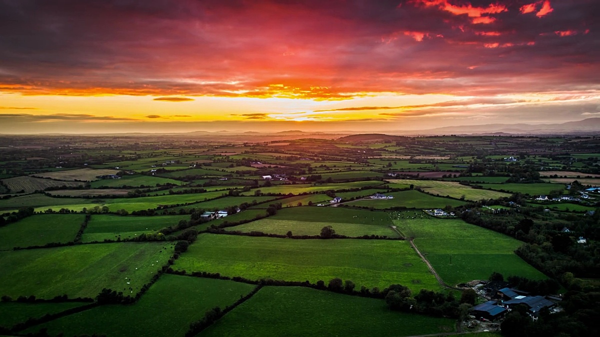 爱尔兰壮观的日落天空下的田野和农田的空中乡村景观