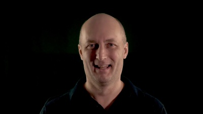 笑着的中年男人看着摄像机。低调特写镜头。