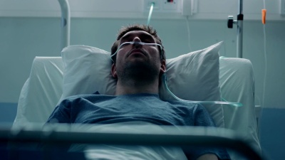 在医院患病的男性病人睡在床上时，他戴着鼻腔插管来帮助他呼吸。病入膏肓的人来了。悲伤和忧郁的场景。