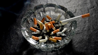 点燃香烟，烟躺在装满烟蒂和烟灰的烟灰缸上