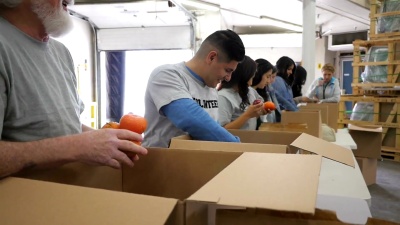 高级男子与不同群体的食物银行志愿者对捐赠箱进行分类